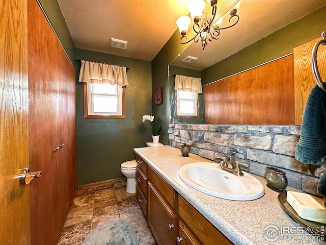 bathroom featuring a chandelier, vanity, toilet, and a wealth of natural light