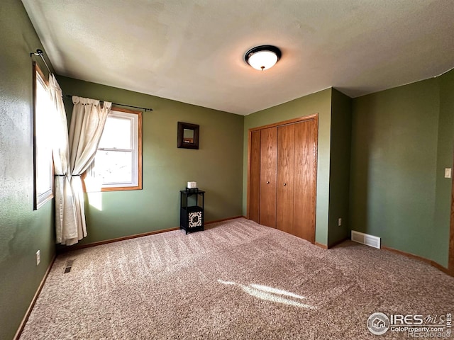 unfurnished bedroom with carpet flooring, a textured ceiling, and a closet