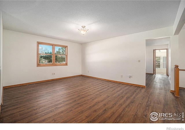 spare room featuring a textured ceiling and dark hardwood / wood-style floors