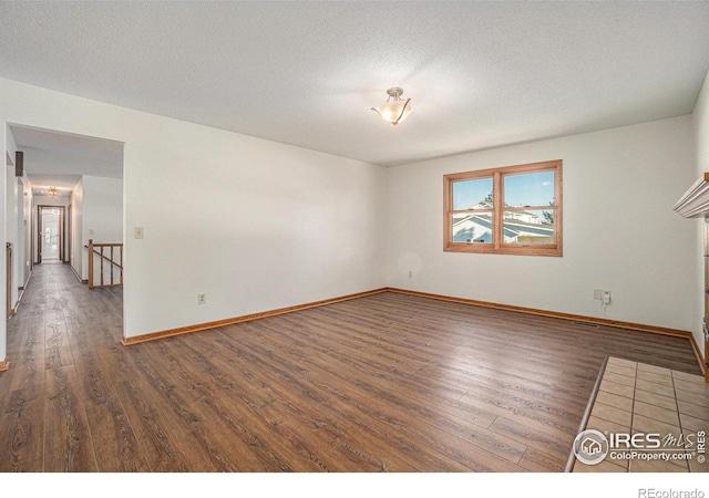 empty room with dark hardwood / wood-style floors and a textured ceiling