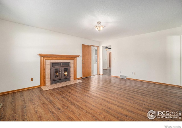 unfurnished living room with a tile fireplace, a textured ceiling, hardwood / wood-style flooring, and ceiling fan