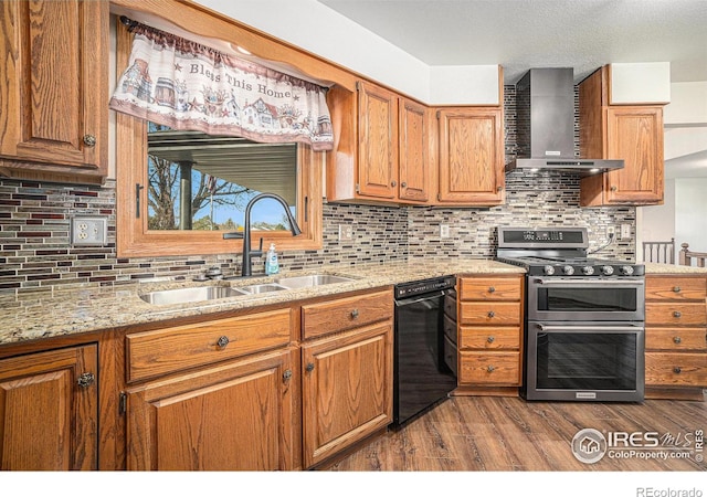 kitchen featuring light wood-type flooring, sink, wall chimney range hood, range with two ovens, and dishwasher