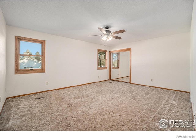 carpeted spare room featuring a textured ceiling and ceiling fan