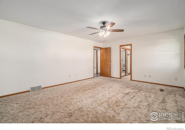 carpeted spare room featuring a textured ceiling and ceiling fan