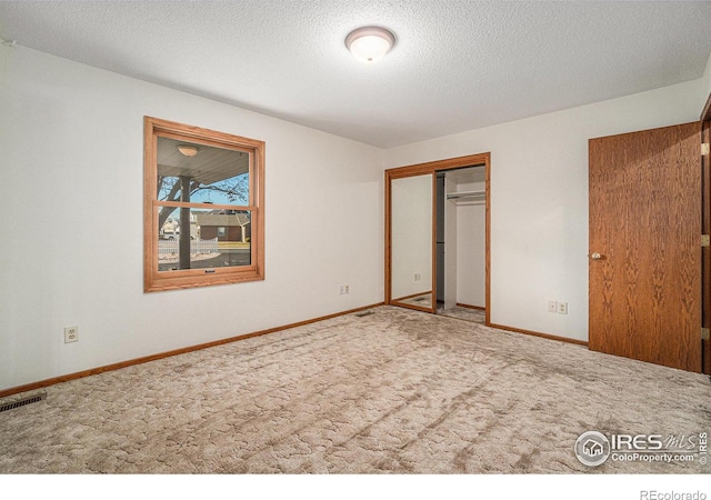 unfurnished bedroom featuring carpet flooring, a textured ceiling, and a closet