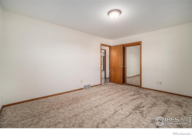 carpeted spare room featuring a textured ceiling