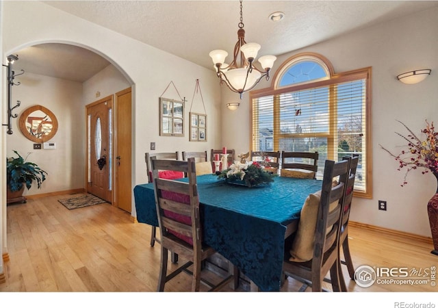 dining room featuring a notable chandelier, light hardwood / wood-style floors, and a textured ceiling