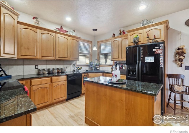 kitchen featuring sink, light hardwood / wood-style flooring, decorative light fixtures, a kitchen island, and black appliances