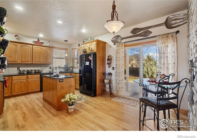 kitchen featuring black appliances, a center island, a healthy amount of sunlight, and hanging light fixtures