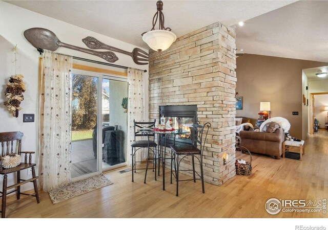 dining area with a fireplace, wood-type flooring, and lofted ceiling