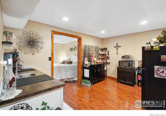 kitchen featuring black refrigerator, light wood-type flooring, and sink