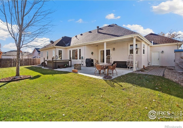 back of house with a lawn, a patio, and a hot tub