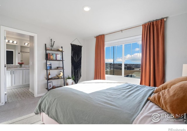 carpeted bedroom with ensuite bathroom and sink