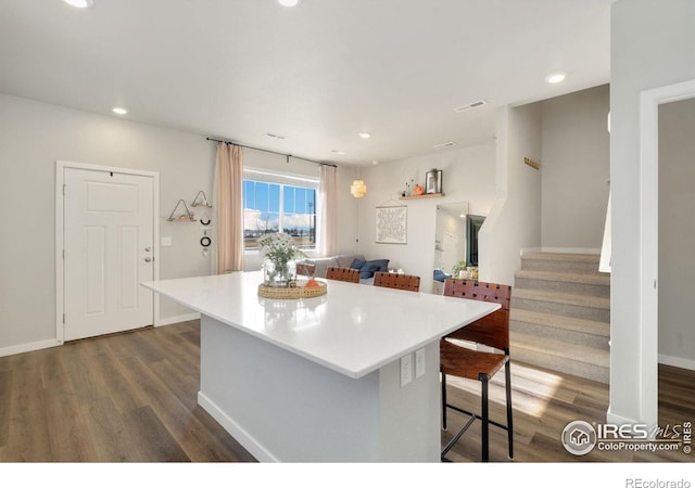 kitchen with a kitchen breakfast bar, dark hardwood / wood-style floors, and a kitchen island