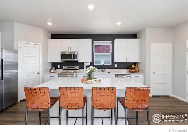 kitchen with a breakfast bar, dark hardwood / wood-style floors, a kitchen island, stainless steel appliances, and white cabinets