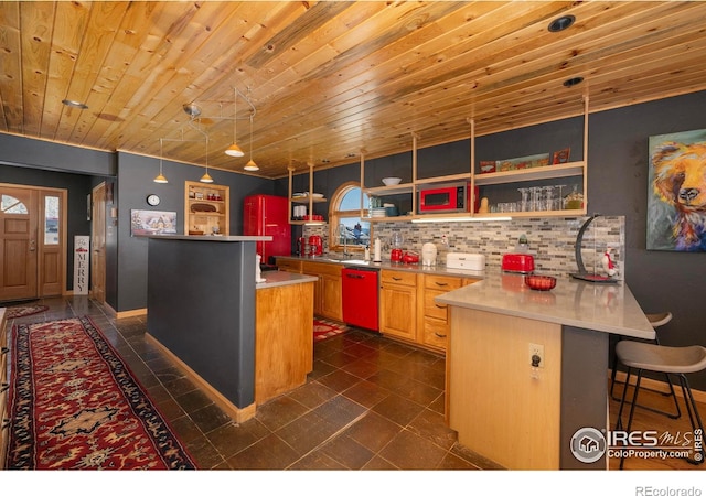 kitchen featuring kitchen peninsula, backsplash, a breakfast bar, pendant lighting, and dishwasher