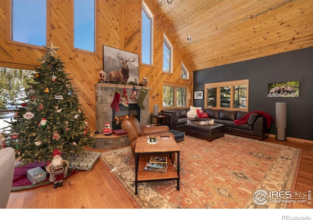 living room with a stone fireplace, high vaulted ceiling, wooden ceiling, and hardwood / wood-style flooring