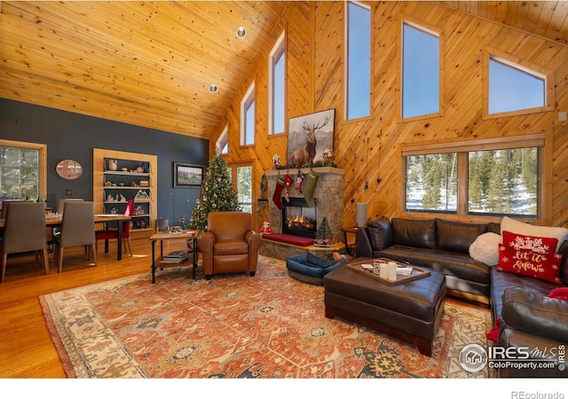 living room with wood-type flooring, high vaulted ceiling, wooden ceiling, and a stone fireplace