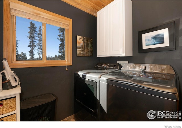 clothes washing area featuring cabinets, separate washer and dryer, and wood ceiling