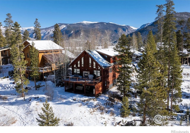 snow covered back of property featuring a deck with mountain view