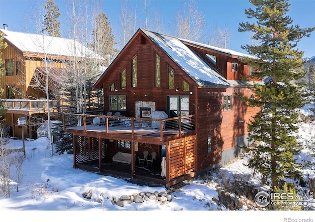 snow covered rear of property featuring a deck