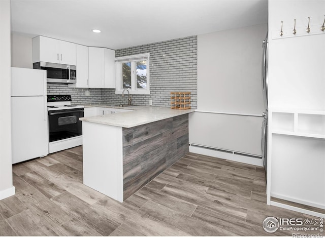 kitchen featuring white appliances, sink, kitchen peninsula, light wood-type flooring, and white cabinetry