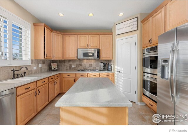 kitchen with a center island, sink, appliances with stainless steel finishes, tasteful backsplash, and light tile patterned flooring