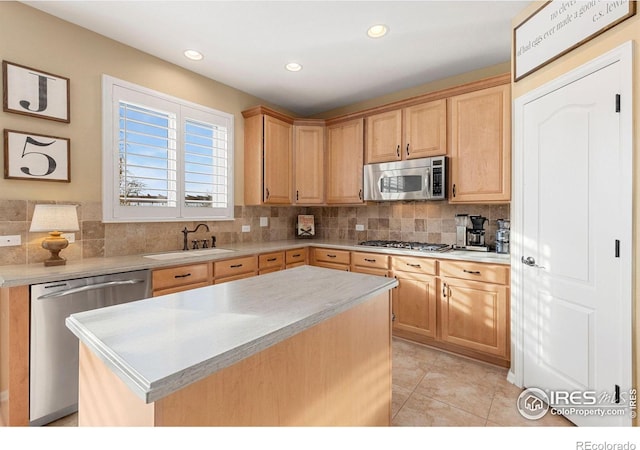 kitchen with tasteful backsplash, stainless steel appliances, sink, light brown cabinets, and a kitchen island