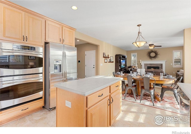 kitchen with light brown cabinetry, a kitchen island, and stainless steel appliances