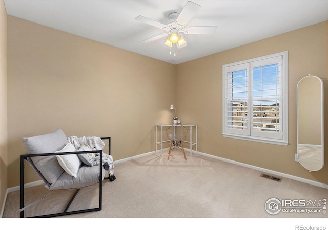 living area with carpet and ceiling fan