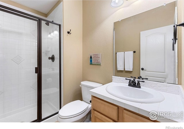 bathroom featuring vanity, a shower with shower door, and toilet