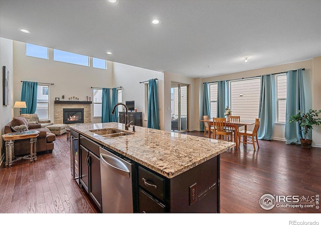 kitchen with dark hardwood / wood-style flooring, sink, light stone counters, and a kitchen island with sink