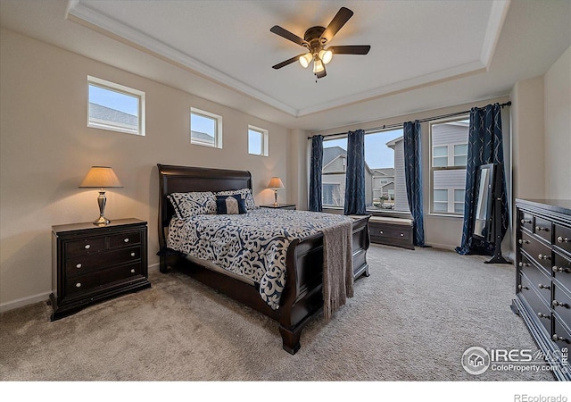 carpeted bedroom with ceiling fan and a raised ceiling