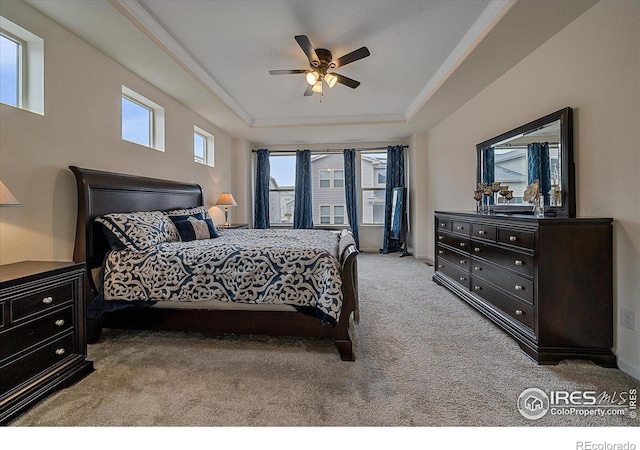 bedroom with ceiling fan, a raised ceiling, and light colored carpet