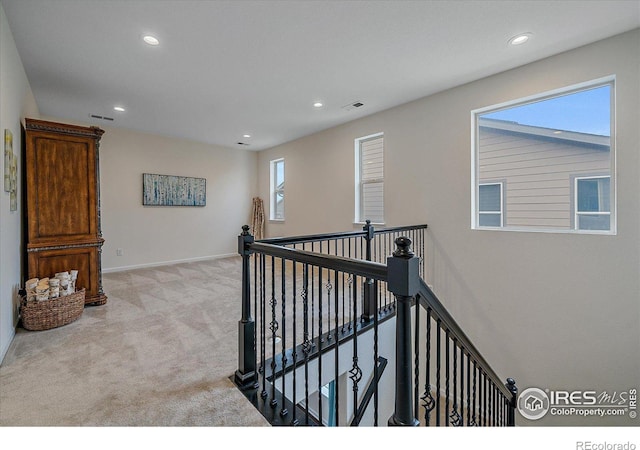 hallway with a healthy amount of sunlight and light colored carpet