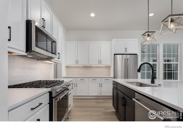 kitchen with hanging light fixtures, premium appliances, white cabinetry, and sink