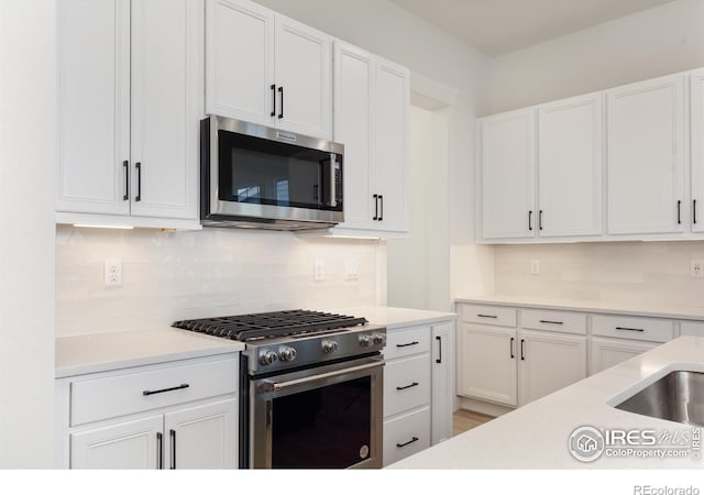 kitchen with sink, appliances with stainless steel finishes, white cabinets, and tasteful backsplash