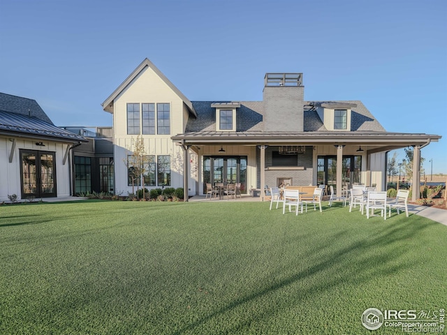 back of property with french doors, a lawn, and a patio area