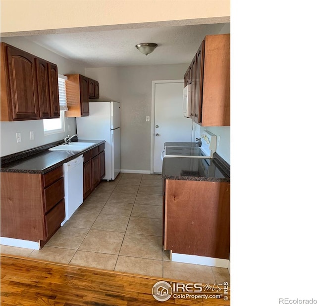 kitchen featuring a textured ceiling, sink, light hardwood / wood-style floors, and white appliances