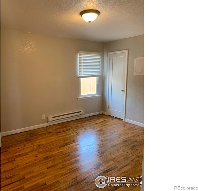 unfurnished room with baseboard heating, hardwood / wood-style floors, and a textured ceiling