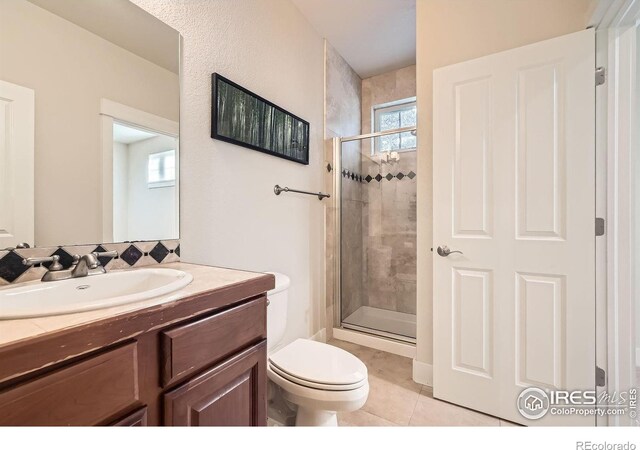 full bathroom with toilet, a stall shower, vanity, and tile patterned flooring