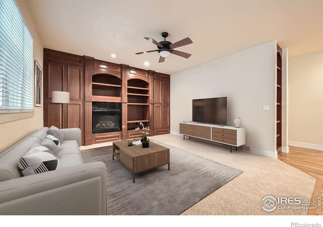 living room with baseboards, a glass covered fireplace, and a ceiling fan