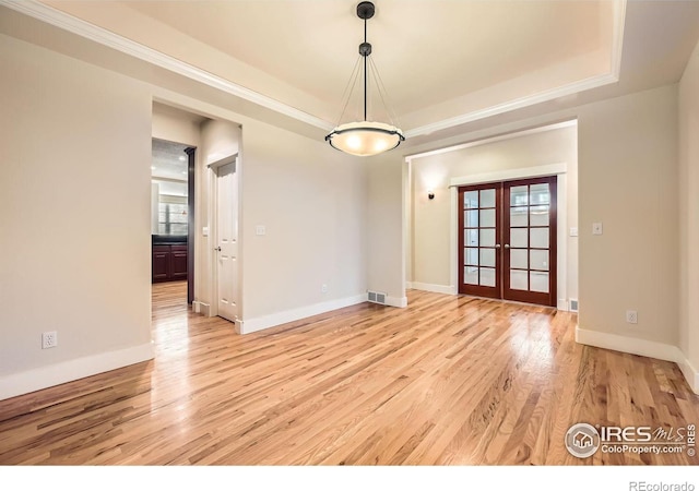 unfurnished room with french doors, a raised ceiling, light wood-style floors, and baseboards