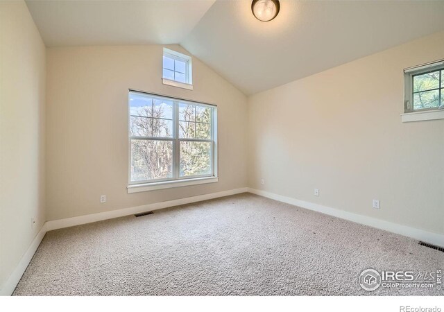 unfurnished room featuring vaulted ceiling, baseboards, visible vents, and carpet floors