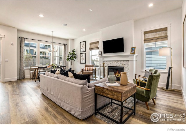 living room with a tiled fireplace, a notable chandelier, and wood-type flooring