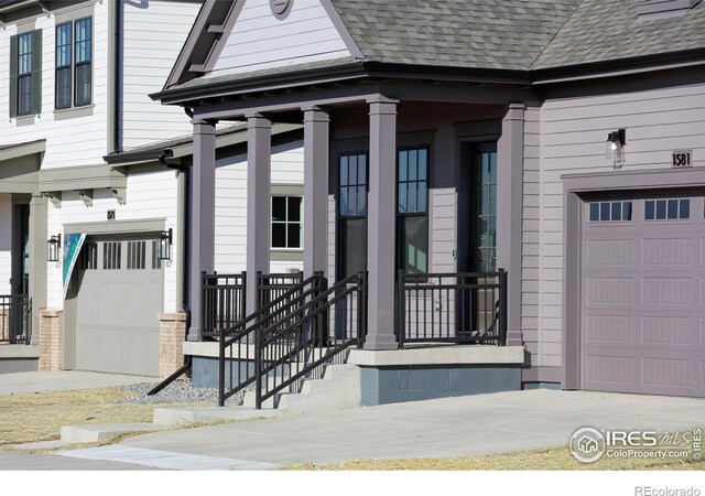 doorway to property featuring an attached garage, a porch, and a shingled roof