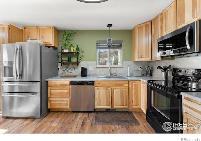 kitchen with backsplash, stainless steel appliances, sink, light brown cabinets, and hanging light fixtures