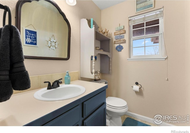 bathroom featuring vanity, toilet, and backsplash