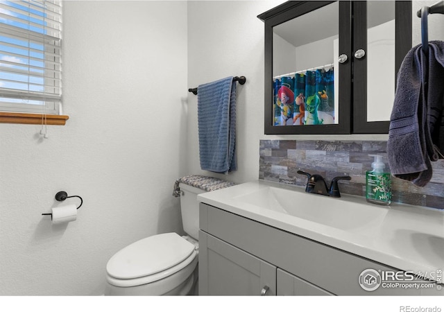 bathroom with decorative backsplash, toilet, and vanity