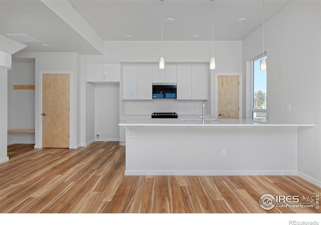 733 Kubat Ln Unit A, Longmont, CO 80503 - kitchen with white cabinetry, decorative backsplash, light countertops, light wood-style flooring, and decorative light fixtures